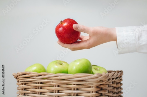 hand above basket  with green apples and red