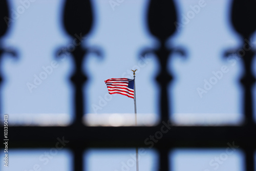 USA flag on pole behind iron fence