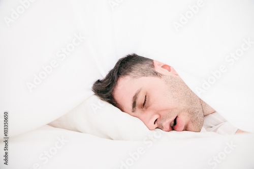 Young man lying in the sheets