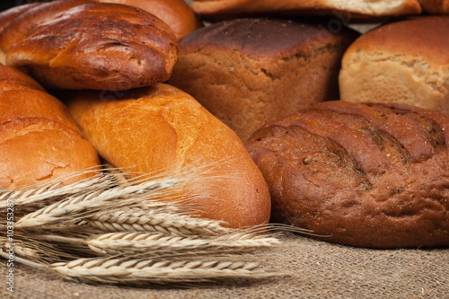 variety of fresh bread with ears of rye background