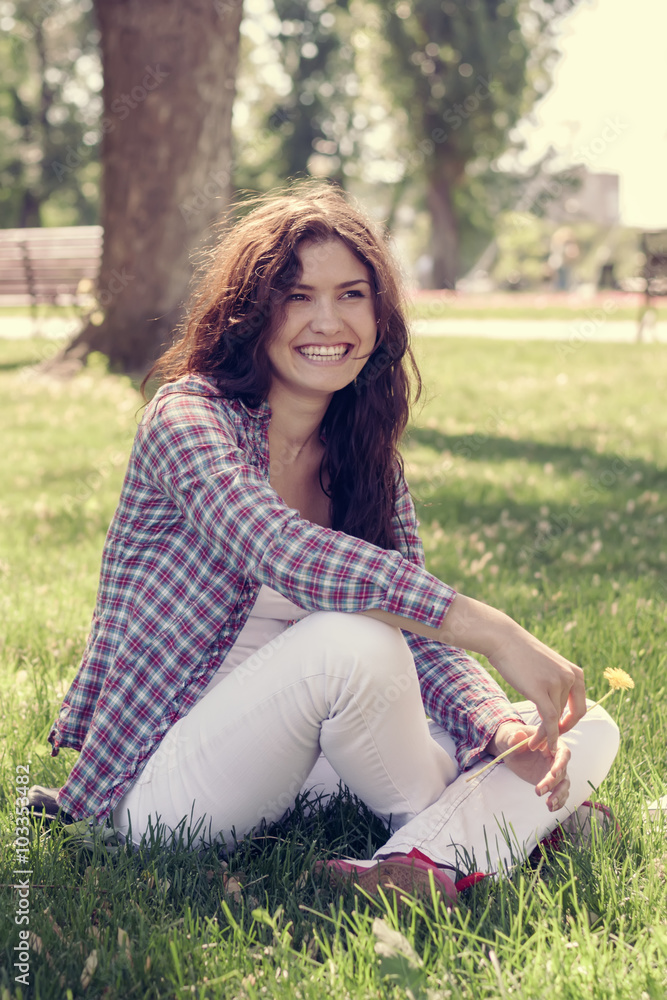 Student sitting in the park on the grass, laughing