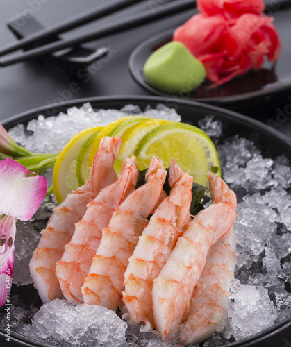 Japanese cuisine, shrimp Sashimi with ice with ginger and wasabi on a black plate photo