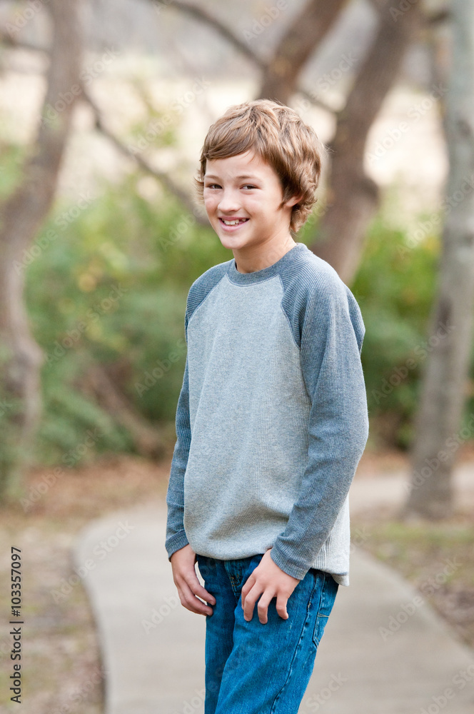 Cute young boy standing on sidewalk looking at camera Cute young boy standing on sidewalk looking at camera