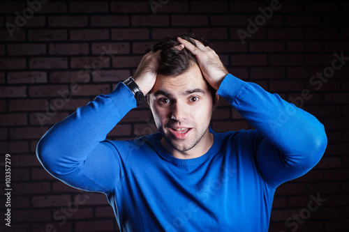 Tablou pe pânză a young  handsome guy scared/ A young frightened boy kept hold of the person