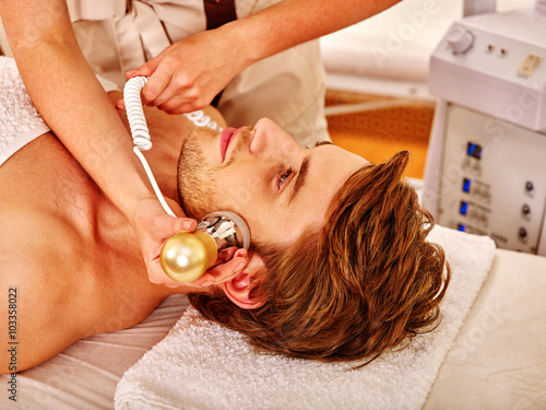 Young man luxuriating on electroporation  facial therapy at beauty salon.  photo