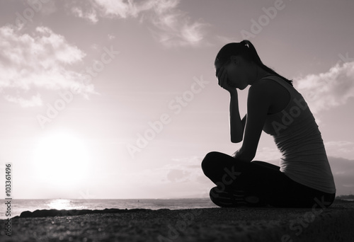 Sad and alone woman sitting on the beach. 