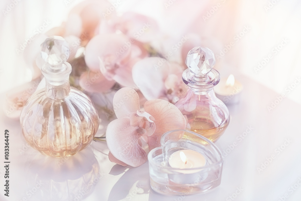 Perfume and aromatic oils bottles surrounded by flowers and cand Perfume and aromatic oils bottles surrounded by flowers and cand