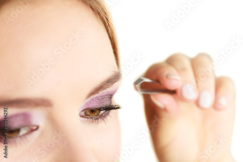 Woman tweezing eyebrows plucking with tweezers © Voyagerix