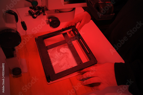 Valokuva Photographer in the laboratory with  enlarger projects the image from a negative
