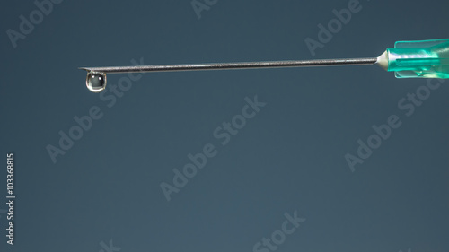 Принти на полотні The tip of a hypodermic needle with a drop of drug, on dark blue background