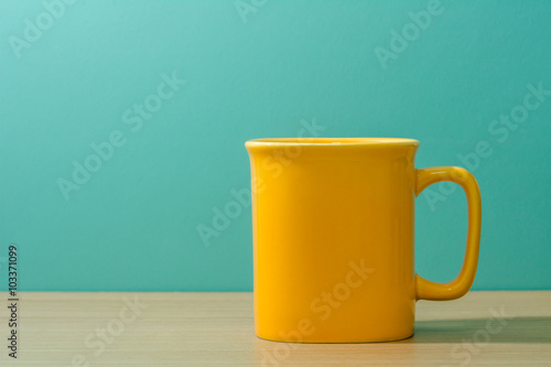 yellow mug on wooden table with green background