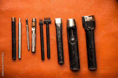 Leather crafting tools on work table with tan color genuine leather photo