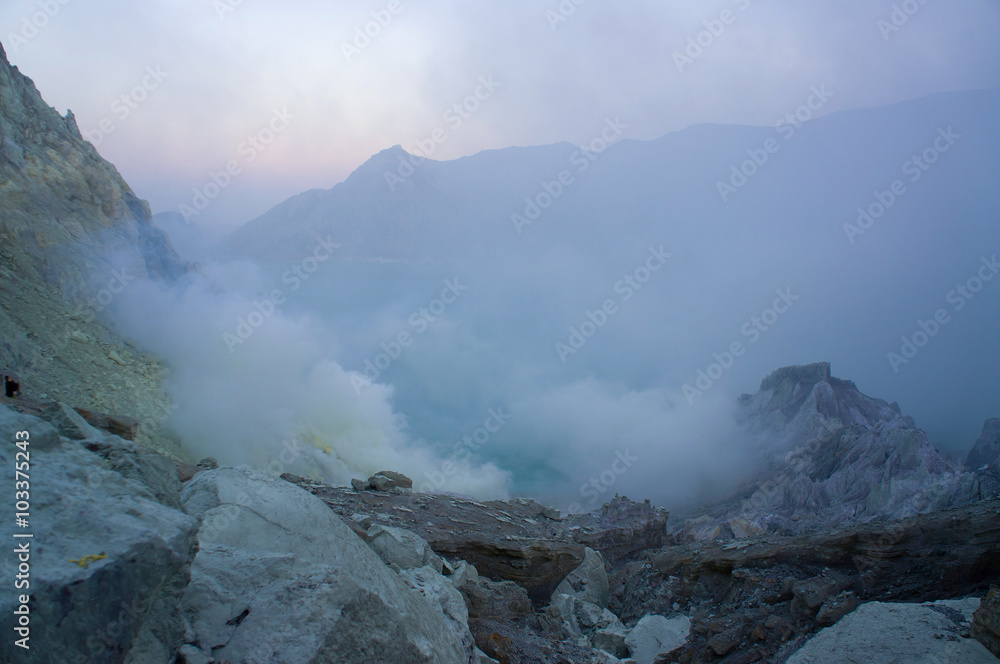 Ijen volcano in East Java contains the world's largest acidic volcanic crater lake, called Kawah Ijen, spewing out sulphur smoke in the morning. Sun is hidden in mist.
