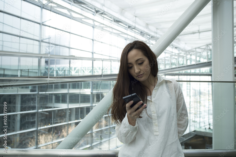 Asian women are looking at the smartphone at the station Asian women are looking at the smartphone at the station