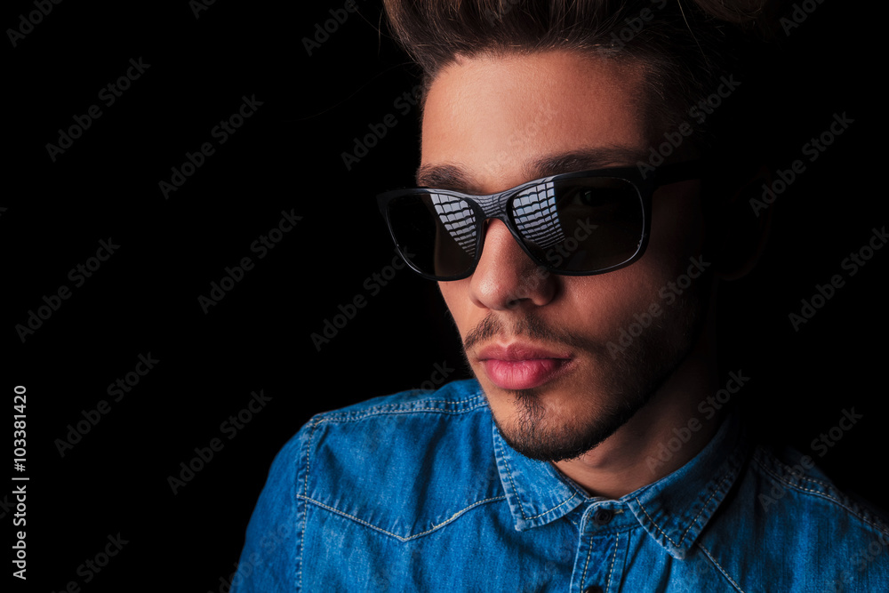 Fototapeta premium portrait of man in denim wearing sunglasses in dark studio