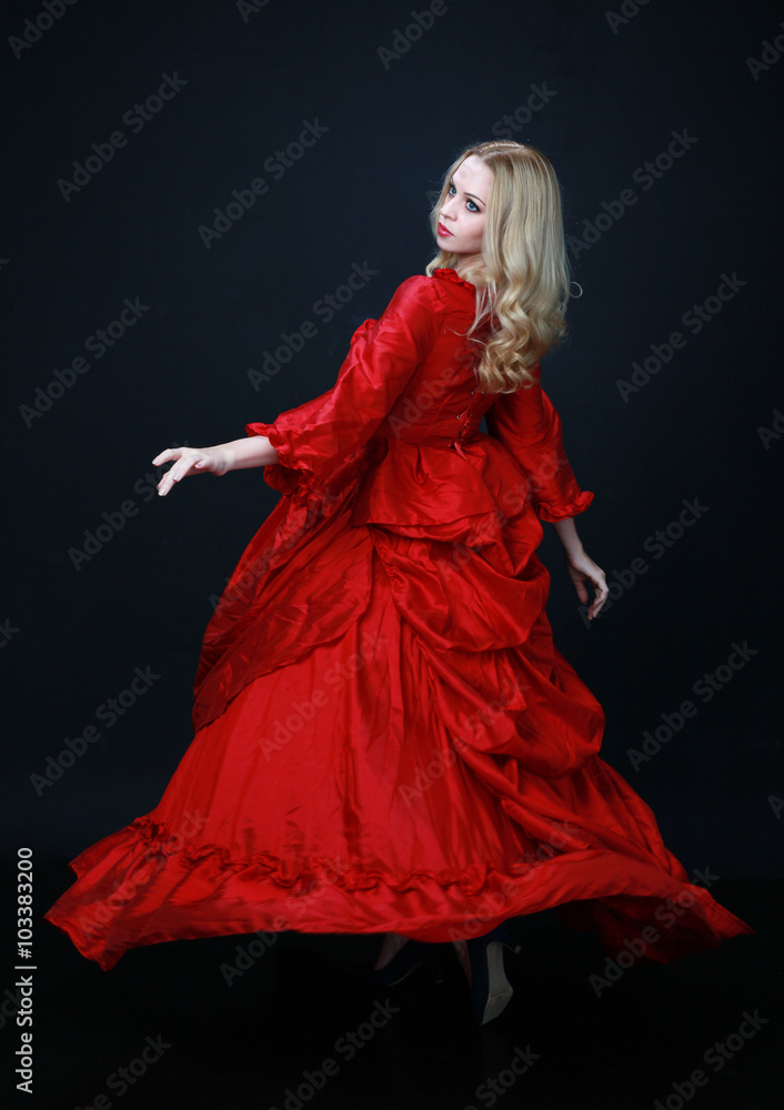 full length portrait of a beautiful blonde woman wearing a historical red silk, victorian era ball gown. full length portrait of a beautiful blonde woman wearing a historical red silk, victorian era ball gown.