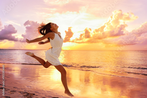 Freedom wellness well-being happiness concept. Happy carefree Asian woman feeling blissful jumping of joy on peaceful beach at sunset. Serenity  relaxation  mindfulness  stress free concepts.