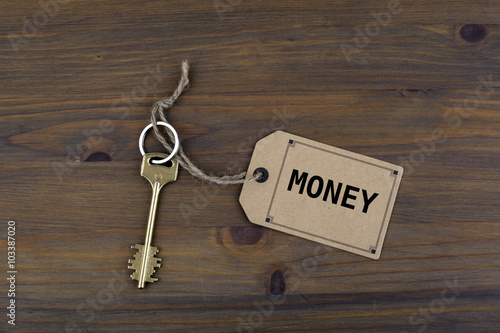 Key and a note on a wooden table with text - Money