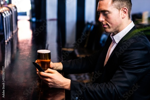 Businessman texting and having a beer