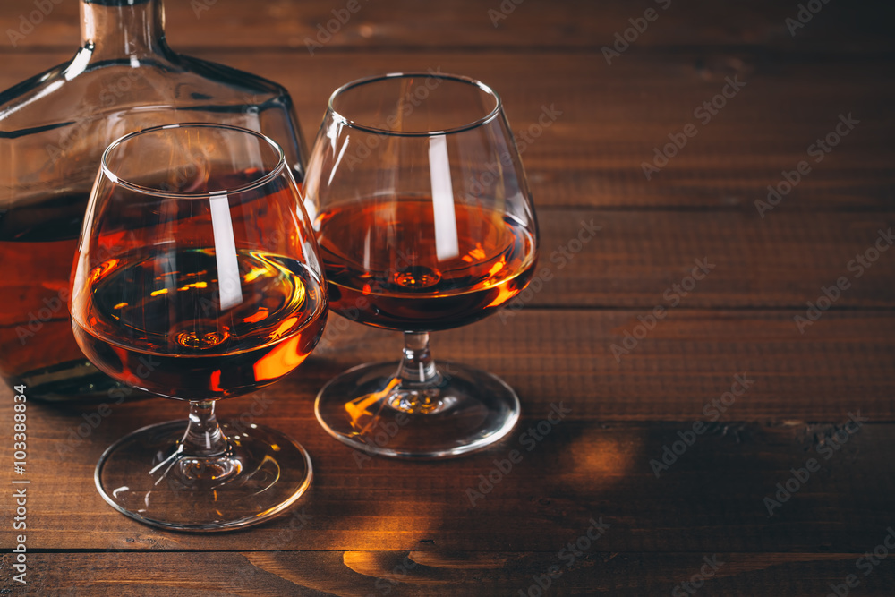 Two glasses of cognac and bottle on the wooden table. Two glasses of cognac and bottle on the wooden table.