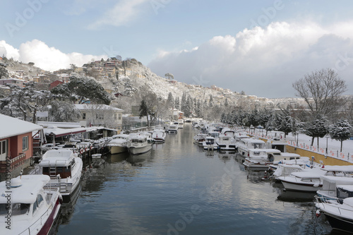 Boats and Yachts covered with snow parked on Goksu Rriver creates very nice landscape with the hill and the trees, Istanbul photo