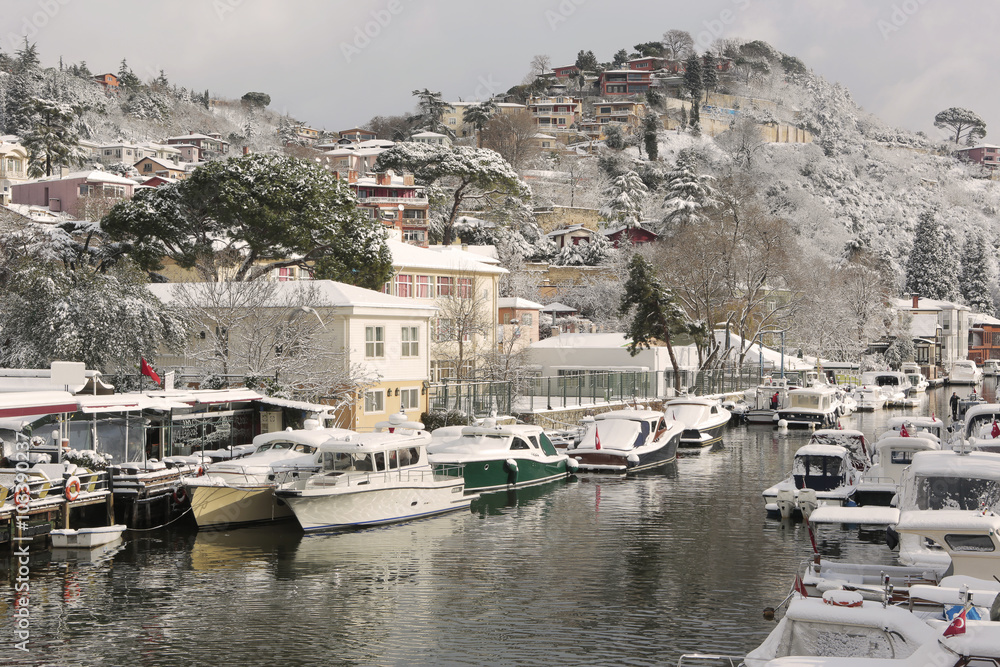 Boats and Yachts covered with snow parked on Goksu Rriver creates very nice landscape with the hill and the trees, Istanbul