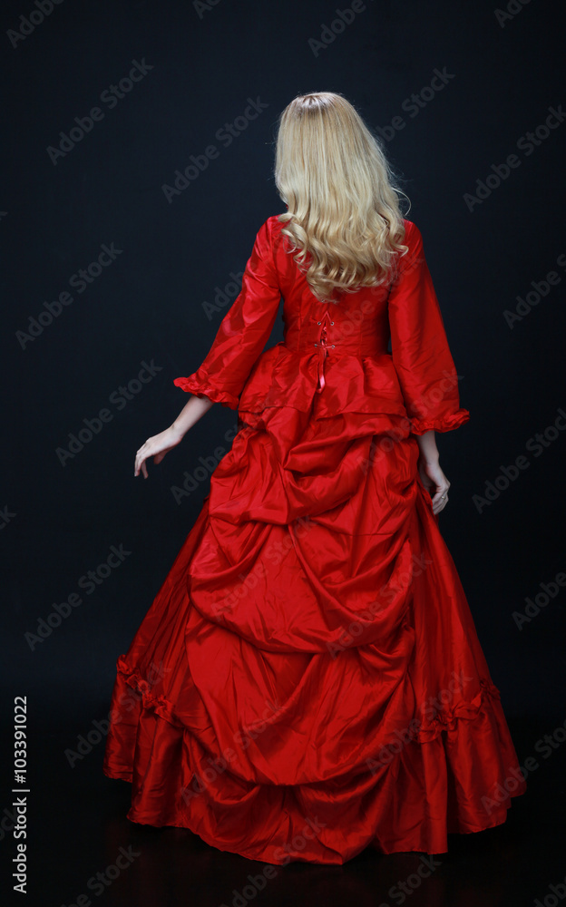full length portrait of a beautiful blonde woman wearing a historical red silk, victorian era ball gown. full length portrait of a beautiful blonde woman wearing a historical red silk, victorian era ball gown.