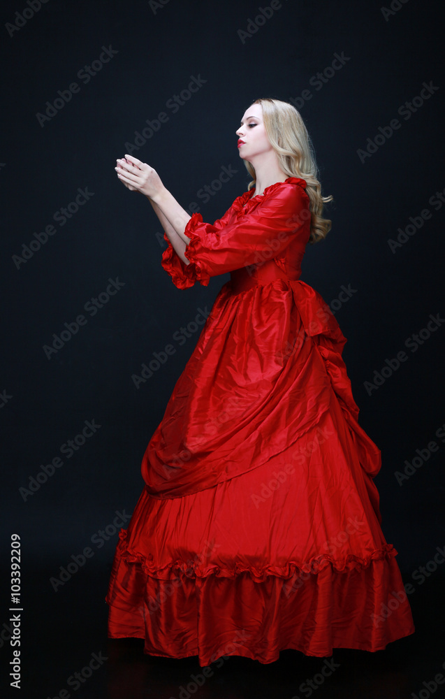 full length portrait of a beautiful blonde woman wearing a historical red silk, victorian era ball gown. full length portrait of a beautiful blonde woman wearing a historical red silk, victorian era ball gown.