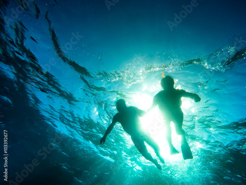 Silhouette of senior couple swimming together in tropical sea - Snorkeling tour in exotic scenarios - Concept of active elderly and fun around the world - Soft focus due to backlight and water density photo