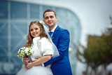 gorgeous happy brunette bride and elegant groom in blue suit wit