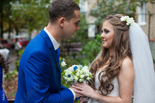 gorgeous happy brunette bride and elegant groom in blue suit wit