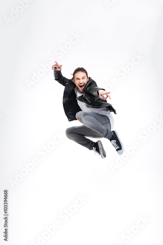 Happy handsome young man showing victory gesture and jumping