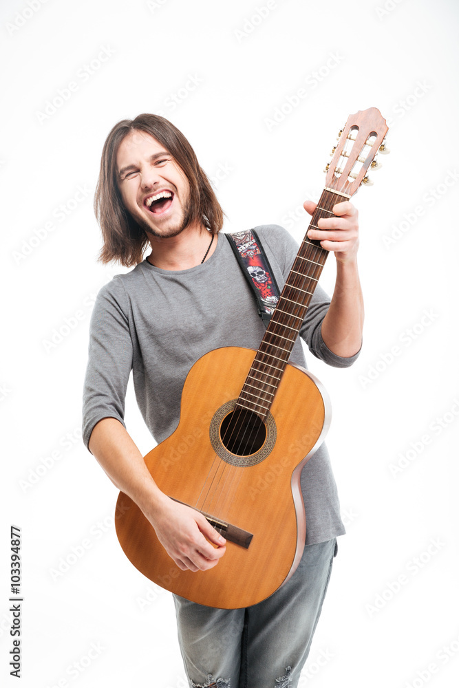 Excited handsome young man with long hair playing acoustic guitar Excited handsome young man with long hair playing acoustic guitar