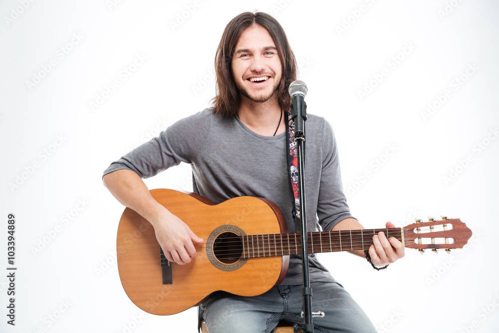 Smiling handsome young man with guitar singing in microphone Smiling handsome young man with guitar singing in microphone