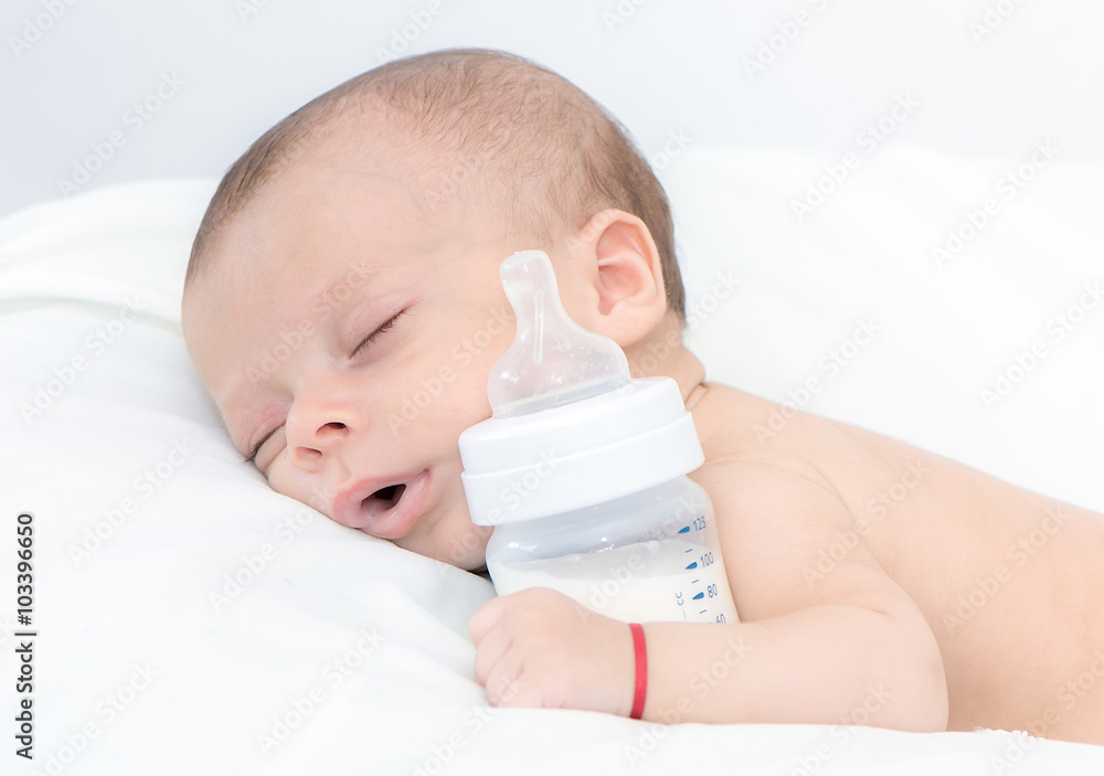 newborn baby curled up sleeping on a blanket with feeding bottle newborn baby curled up sleeping on a blanket with feeding bottle