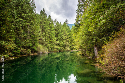 amazing emerald waters of a quiet river in the middle of a forest of pines trees in the rocky mountains of british columbia