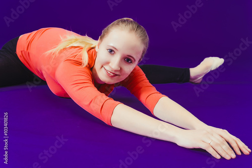 Woman doing stretching exercises on the floor at the gym