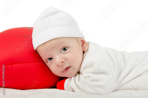 Small baby laying on red pillow isolated on white background