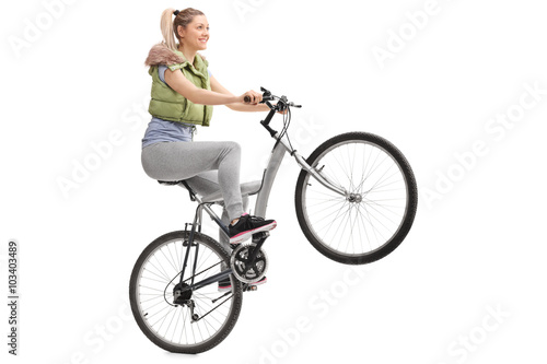 Young woman doing a wheelie on a bicycle