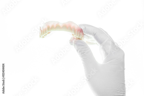 denture and handglove on white background photo