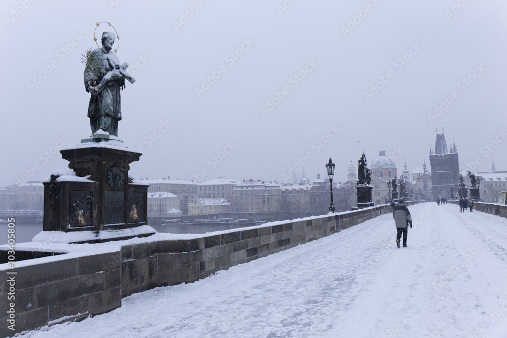 Snowy foggy Prague Charles Bridge with its baroque Sculptures with Old Town, Czech Republic