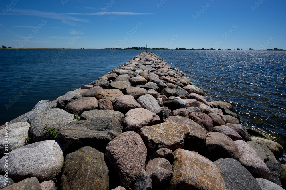 Embedded stones. Rocky beach, peaceful sea, harbor. Mole in Munalaid, Estonia. Baltic sea, Europe
