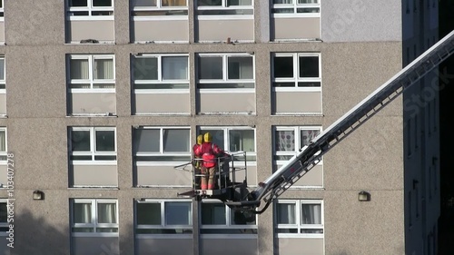 Two fire fighters being lifted up on a hydraulic platform to an residential apartment balcony after an accidental explosion of an aerosol can blew the front of the balcony out.