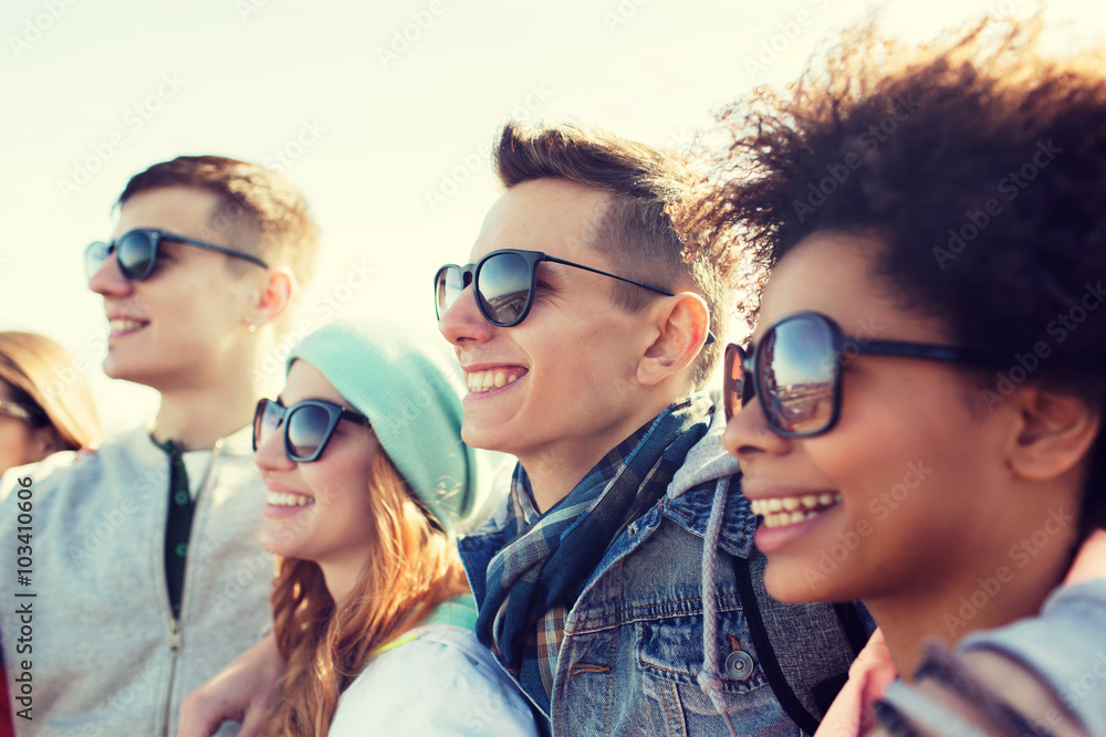 happy teenage friends in shades hugging outdoors happy teenage friends in shades hugging outdoors