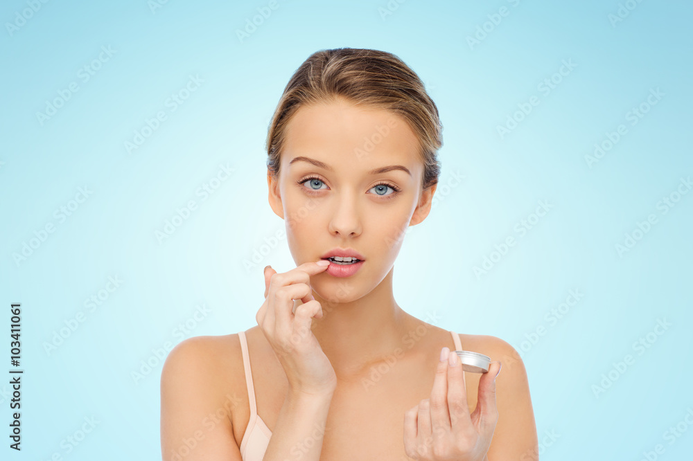 young woman applying lip balm to her lips young woman applying lip balm to her lips