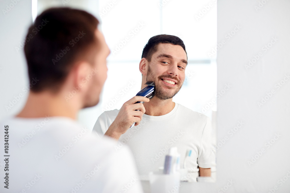 Fototapeta premium man shaving beard with trimmer at bathroom