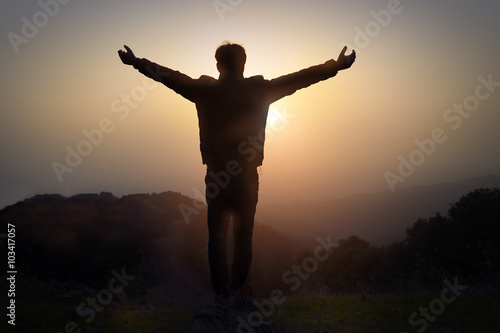 Man with arms raised at sunset on the mountain
