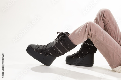 Woman's legs in beige pants and moon boots.