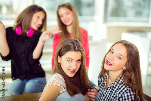 Portrait of four young women sitting at the table in the cafe, selective focus