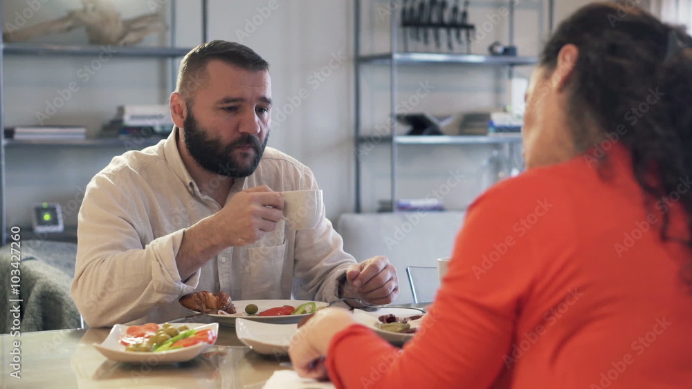 Bored, resentful couple sitting by the table during breakfast
Bored, resentful couple sitting by the table during breakfast